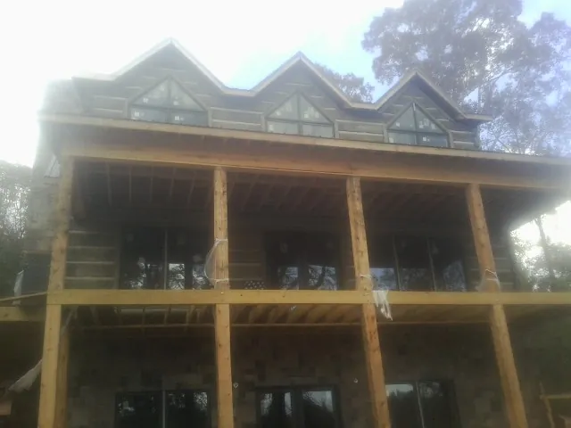 Dormers and porch framing on a large log home under construction — Roof Coating work by our crew in Decatur